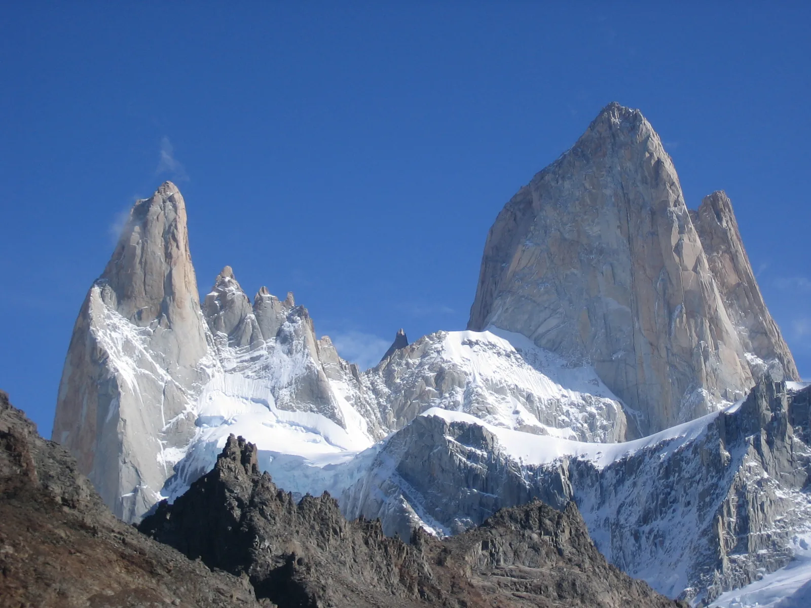 The granite peaks of Mount Fitz Roy in Patagonia under a deep blue sky, with snow and glaciers below